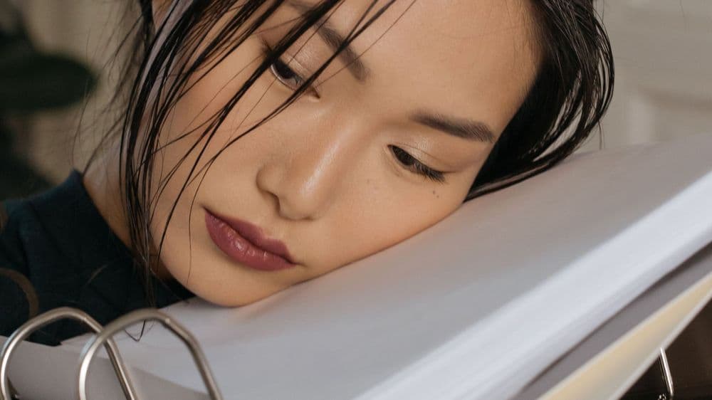 A tired professional resting her head on her arm at her desk