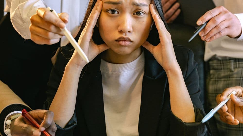 A young professional under pressure as colleagues point at her work