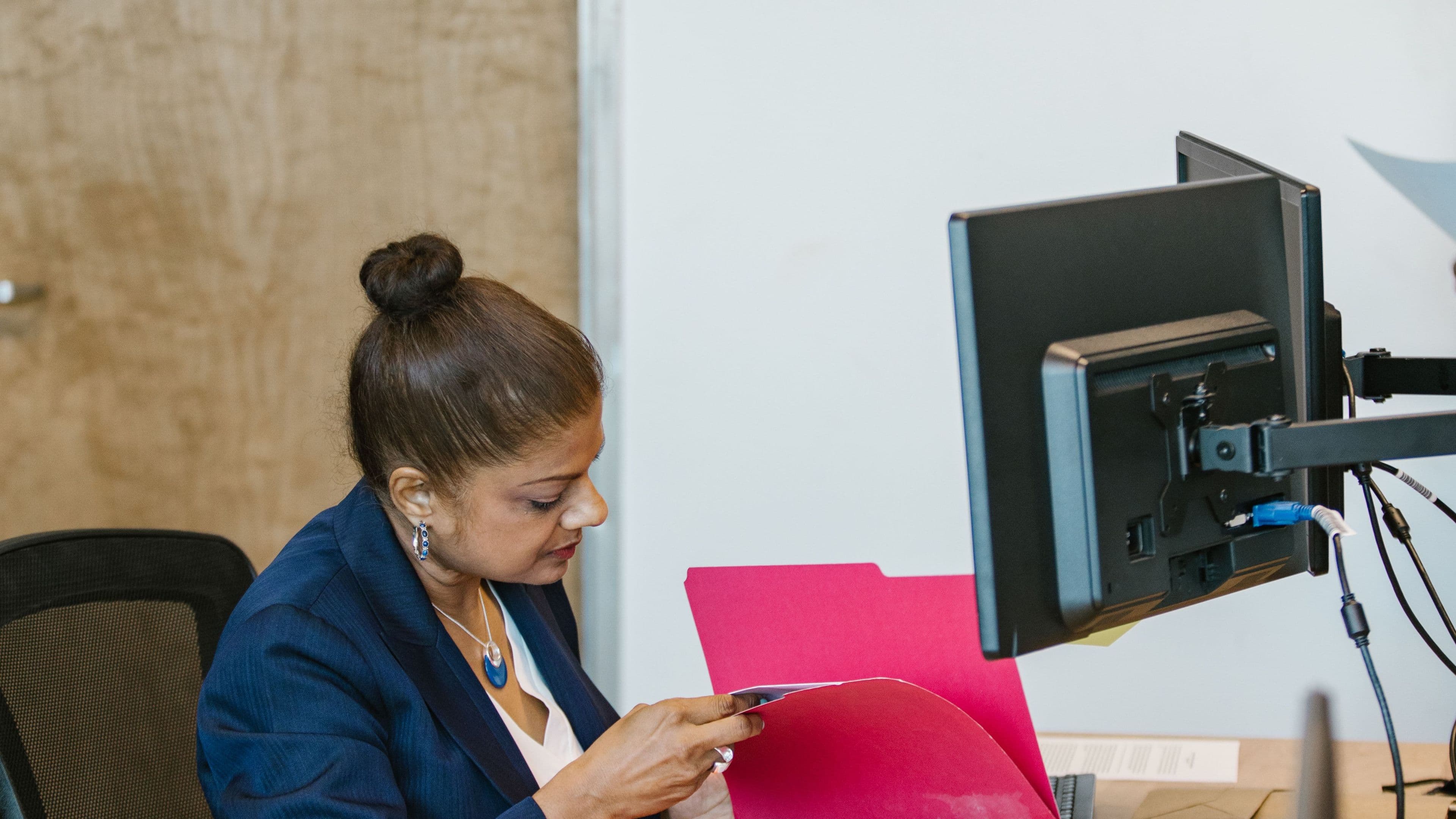 An administrator working through documents at her monitor